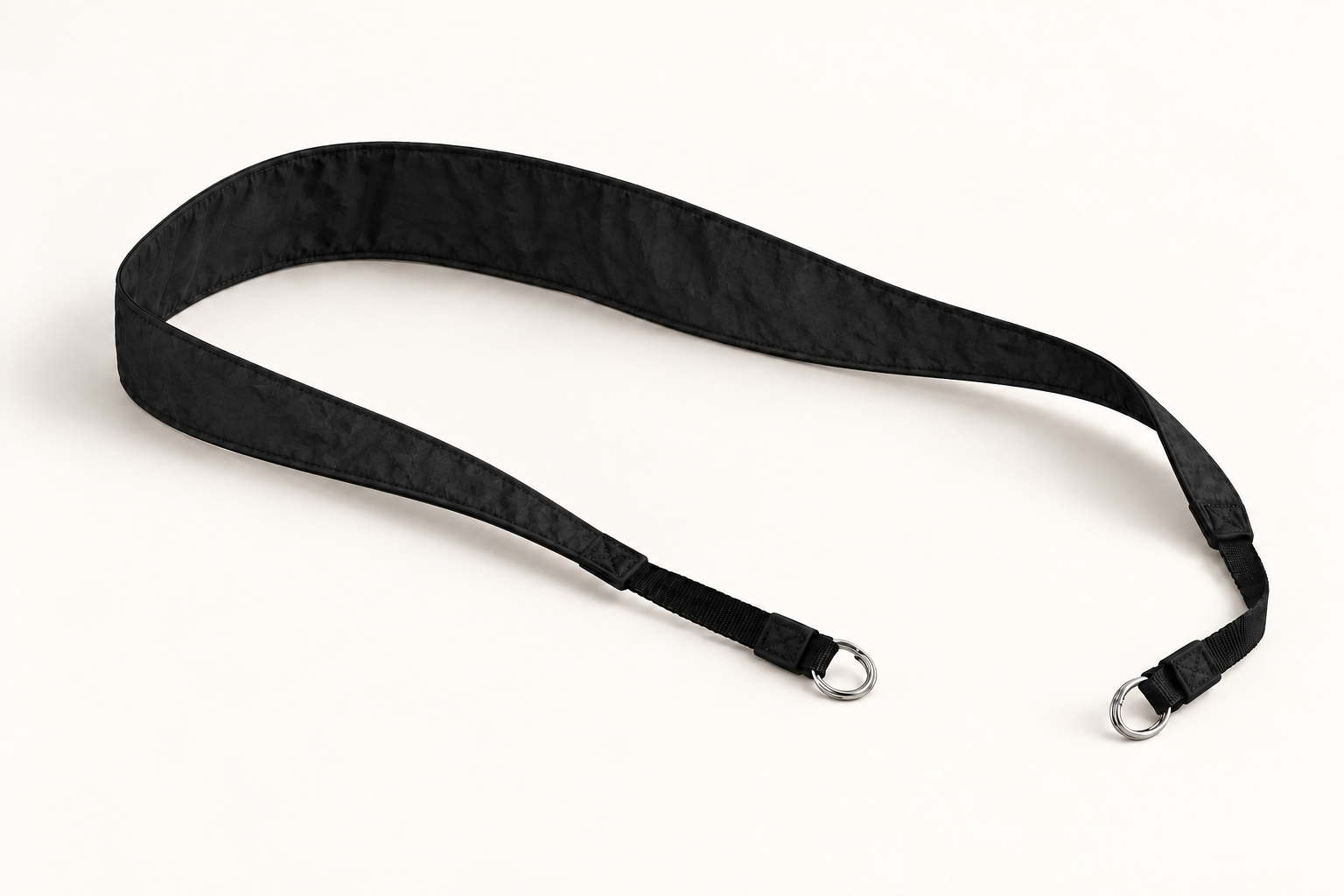 Monofloat camera strap concept in black, with a wide back section tapering toward split-ring ends for camera lugs.